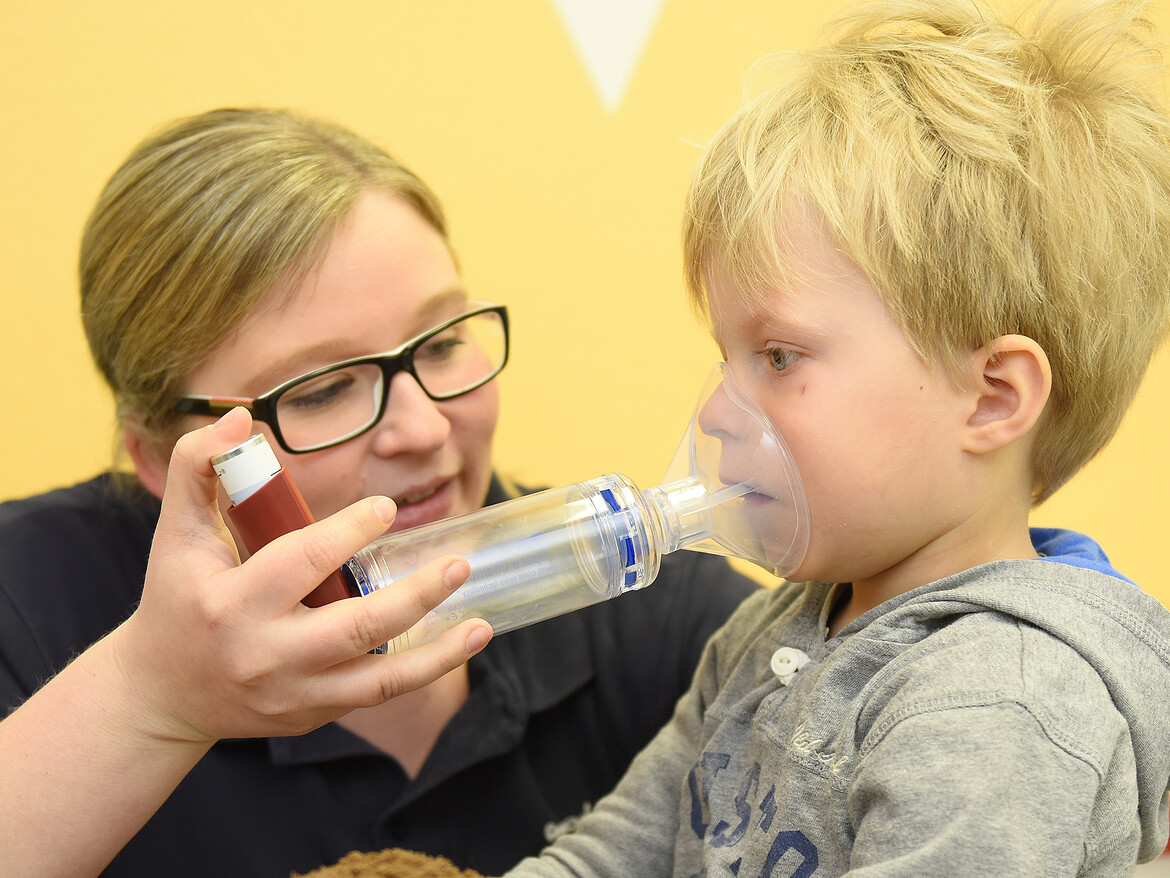 Ein Kleinkind inhaliert mit Hilfe einer Erzieherin im Kinderland des Marianne van den Bosch Hauses.