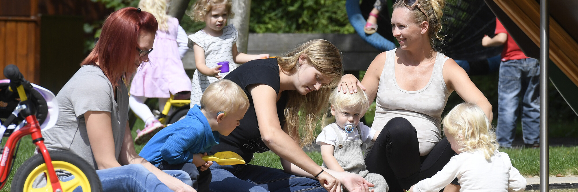 Mütter spielen mit ihren Kindern auf dem großzügigen Außengelände des Marianne van den Bosch Hauses.