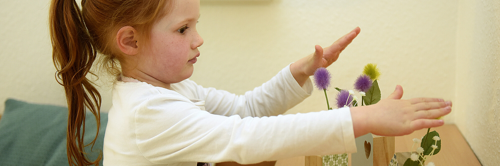 Ein Kind spielt mit Holzblumenvasen im Marianne van den Bosch Haus.