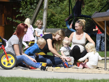 Mütter spielen mit ihren Kindern auf dem großzügigen Außengelände des Marianne van den Bosch Hauses.