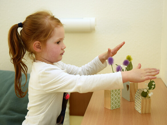 Ein Kind spielt mit Holzblumenvasen im Marianne van den Bosch Haus.
