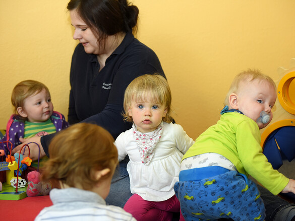 Eine Erzieherin kümmert sich im Kinderland des Marianne van den Bosch Hauses um eine Gruppe Kleinkinder.