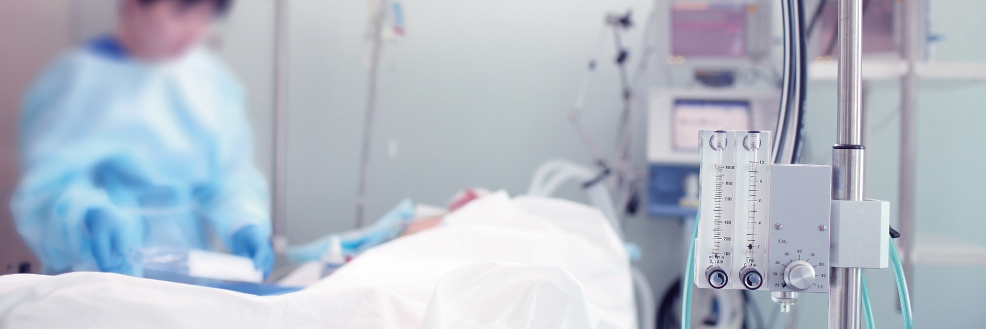 Eine Pflegekraft steht am Bett eines Patienten auf der Intensivstation.