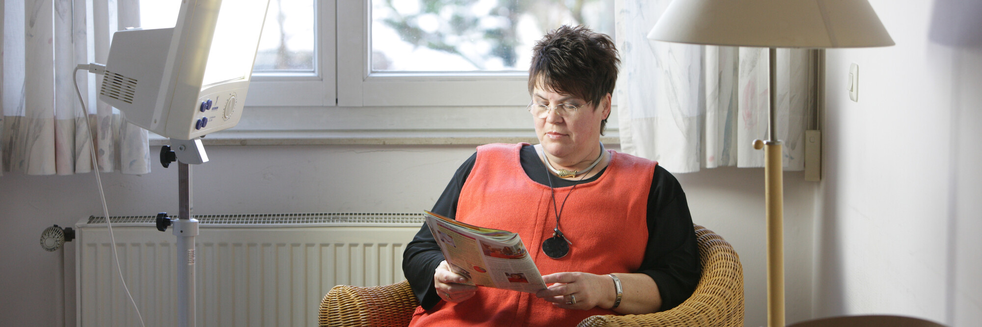 Eine Patienten des St. Nikolaus-Hospitals liest während der Lichttherapie in einem Magazin.