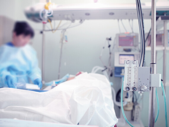 Eine Pflegekraft steht am Bett eines Patienten auf der Intensivstation.