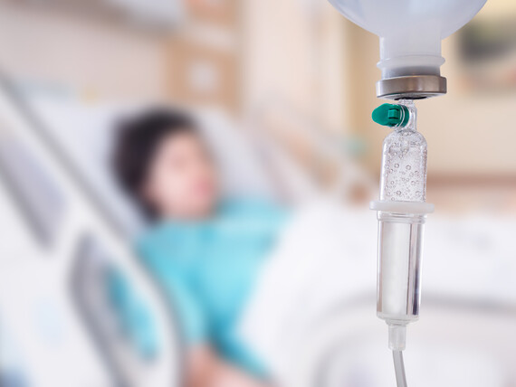 Im Vordergrund eine angehängte Chemotherapie, im Hintergrund eine Patientin der Onkologie.