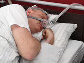 Ein Patient mit Sauerstoffmaske schläft im Schlaflabor.