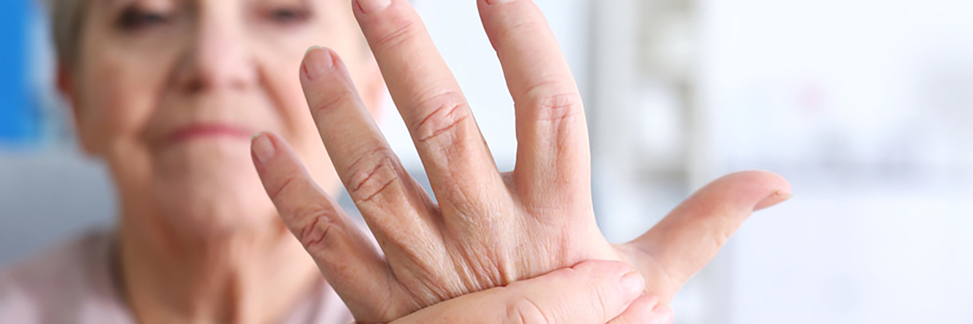 Eine Patientin hält sich die Hand vor Schmerzen.