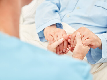 Blick von hinten über die Schulter: Hände halten Hände.