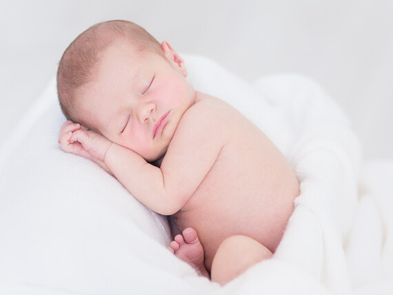 Ein neugeborenes Baby schläft und kuschelt mit einem Handtuch.